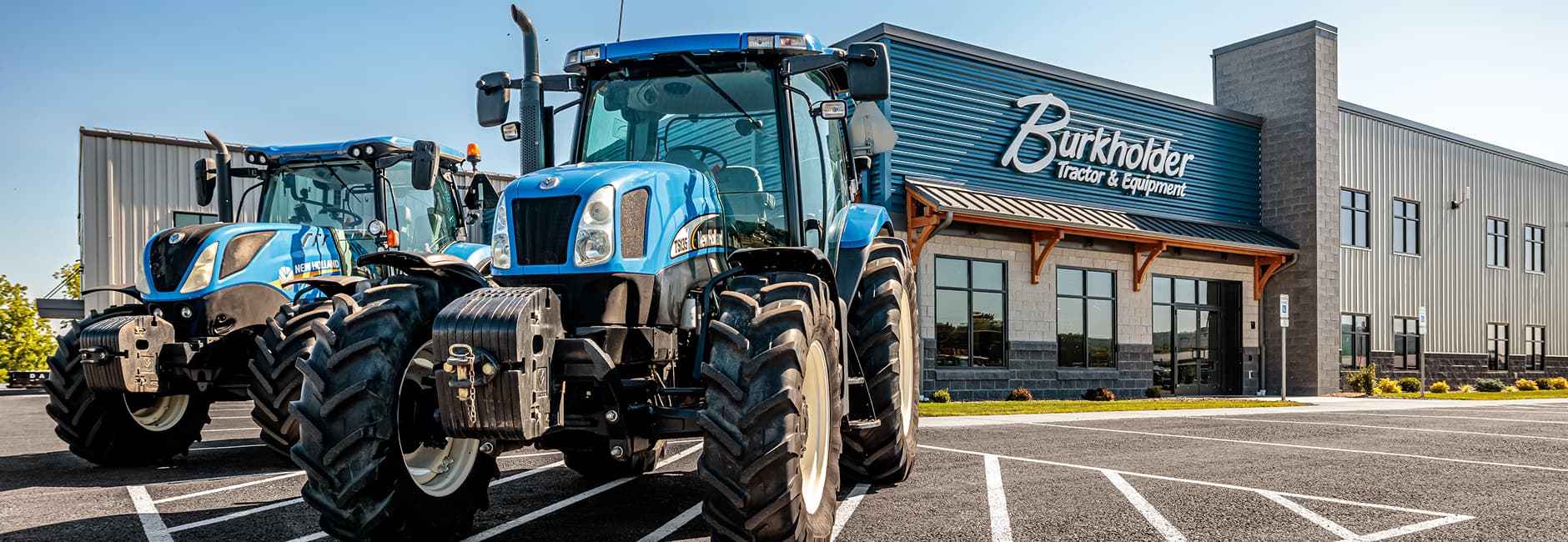 two blue tractors in front of the workshop
